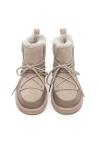 Botas beige hasta el tobillo con un suave forro de piel sintética y parte superior de ante. Cuentan con punta redondeada y cierre de cordones. Suela de goma texturizada para mayor agarre.