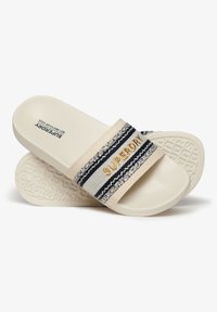 Beige schuifsandalen met een marineblauwe en witte gestreepte band met "SUPERDRY" in goud. Geltexteerde witte zool. Glad materiaal.