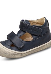 Navyblå läder skor för små barn med två kardborreband, utskärningsdesign och en vit gummisula. Slät textur med lätt slitage på sulan.