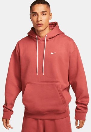 Rød bomulds hoodie med hvid snor, frontlomme og lille hvid Nike-logo på brystet. Løs pasform med ribbede manchetter.