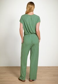 Groene en witte gestreepte loungewear set met korte mouwen en brede broekspijpen. Materiaal lijkt zacht; elastische tailleband en relaxte pasvorm.