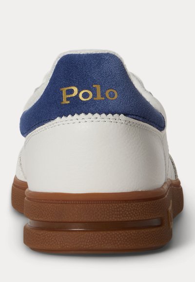 Baskets blanches avec semelle marron et languette de talon en daim bleu avec marquage texte doré "Polo".