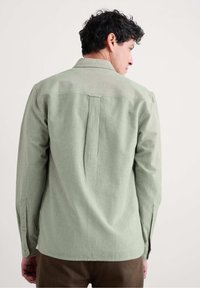 Lichtgroene langwerpige shirt met een stevige structuur, rugplooi detail en knoopmanchetten. Casual ontwerp, gemaakt van zachte stof.