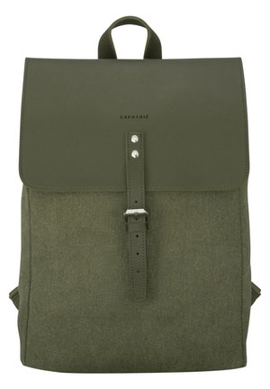 Olive green fabric backpack with leather flap and strap closure, top handle, and "EXPATRIÉ" branding on the flap.