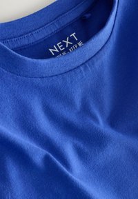 T-shirt en coton bleu avec couture de col visible et étiquette intérieure imprimée portant la mention "NEXT".