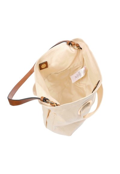 Kremowa torba na ramię z płótna z brązowymi skórzanymi uchwytami i małą wewnętrzną kieszonką z widoczną białą metką pielęgnacyjną wewnątrz.