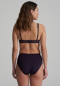 Set di lingerie viola composto da un reggiseno abbinato e da slip a vita alta. Il tessuto ha una texture liscia con dettagli in pizzo ondulato sulle spalline.