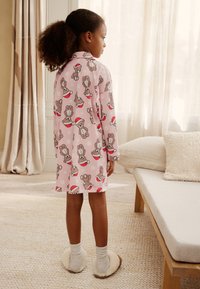 Pink pajama dress featuring a bear print, long sleeves, and round collar. The design includes white polka dots and festive red accents.