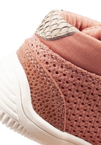 Scarpa sportiva rosa chiaro con una tomaia in rete traspirante, dettagli testurizzati e una suola in gomma bianca con scanalature laterali.