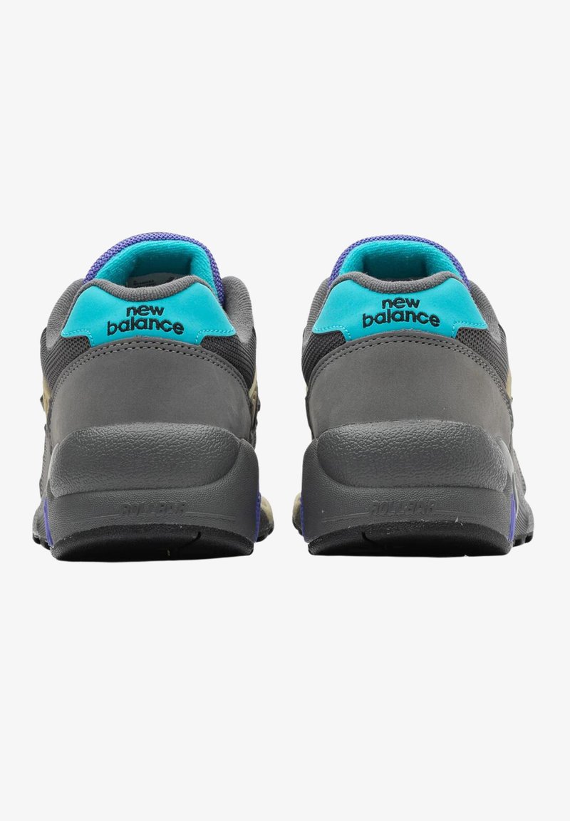 Baskets de sport grises avec une surface texturée, présentant un accent turquoise et violet sur le col et le logo, conçues pour le confort et le soutien.