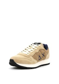 Beige suède sneakers met marineblauwe accenten, witte zool en platte veters. Voorzien van een geometrisch logo aan de zijkant en een gevoerde kraag.