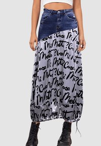 Falda de mezclilla y satén con una sección superior azul y un patrón de texto negro sobre un fondo plateado. Cuenta con un dobladillo con cordón y bolsillos laterales.