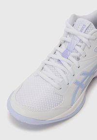Chaussure de sport blanche avec un dessus en maille texturée, présentant des accents et des lacets lavande. Le design comprend un logo Asics proéminent et une semelle courbée.