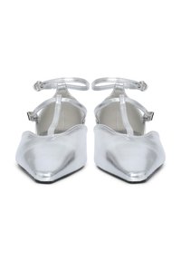 Par de zapatos planos de punta afilada en plata brillante con correas alrededor del tobillo y correas en forma de T, vistos de frente.