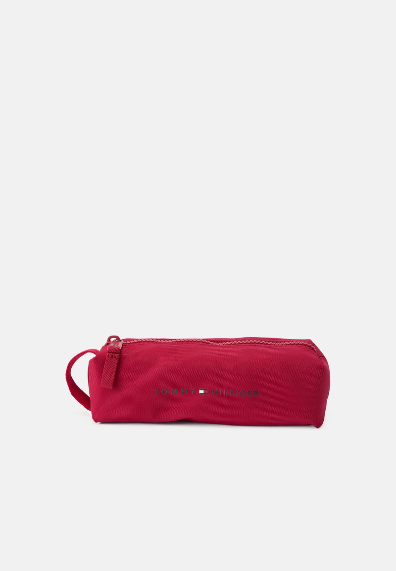 Étui à crayons en nylon rouge avec fermeture éclair, boucle sur le côté et logo "TOMMY HILFIGER" en argent. Design compact et cylindrique.