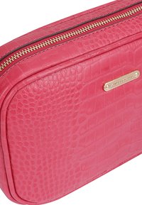 Roze textuur leren pouch met gouden ritssluiting en een rechthoekige gouden merktekenplaat aan de voorkant.