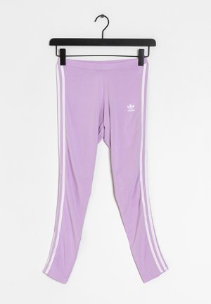 Leggings lavande Adidas avec bandes blanches sur les côtés et logo, accrochés à un cintre noir sur fond blanc.