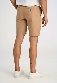 Beige linneblandade shorts med texturerad väv, i slim fit med två bakfickor, parat med vita sneakers.
