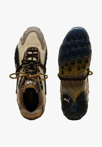 Scarpe sportive beige e nere con tomaia in camoscio e pelle testurizzati, caratterizzate da punta arrotondata, lacci avvolgenti e suola in gomma con motivo.