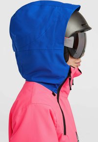 Felle roze skijack met een blauwe capuchon, voorzien van een ritssluiting aan de voorkant, verstelbare banden en skibril, die contrasterende kleuren en materialen laat zien.