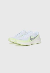 Weiße Sportschuhe mit einem atmungsaktiven Mesh-Obermaterial, neon-gelben Akzenten, silbernem Logo und strukturiertem Sohlenprofil für besseren Halt.