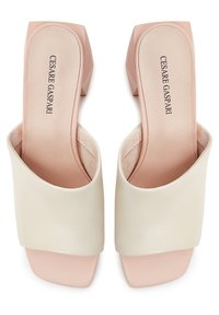 Due sandali con tacco a cuore d'oca e design frontale aperto, realizzati con tomaia in pelle crema e tacco blocco rosa soft. Texture liscia e forma moderna.