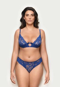 Modrý krajkový spodní prádlo s podprsenkou ve tvaru "v" s tenkými ramínky a odpovídajícími tangy. Všimněte si květinového krajkového vzoru a průhledných detailů.