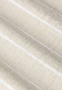 Crèmekleurige stof met een gestructureerde weving, voorzien van subtiele witte horizontale strepen. Zacht en lichtgewicht met een natuurlijke uitstraling.