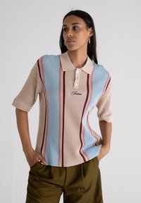 Lightweight, knitted polo shirt featuring alternating stripes in beige, blue, and red, with a three-button collar and embroidered logo.