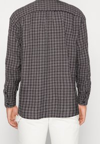 Schwarz-weiß kariertes Langarmhemd mit Knopfmanschetten, einem geraden Rückendesign und weichem, strukturiertem Stoff.