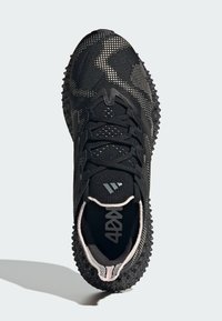 Black athletic shoe featuring a textured upper with a pattern of small dots, thick laces, and a spiked rubber outsole for traction.