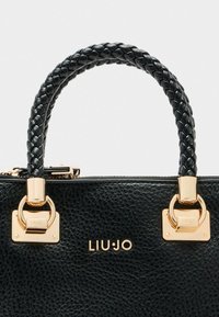 Sac à main en cuir noir avec une poignée tressée, des accents en matériel doré et une surface texturée. Présente le nom de la marque "LIU·JO" en relief.