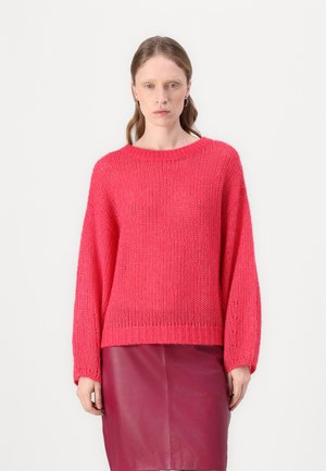 Gebreide roze trui met een brede hals en lange, losse mouwen, gecombineerd met een kastanjebruine leren rok. Getextureerde stof met een relaxte pasvorm.