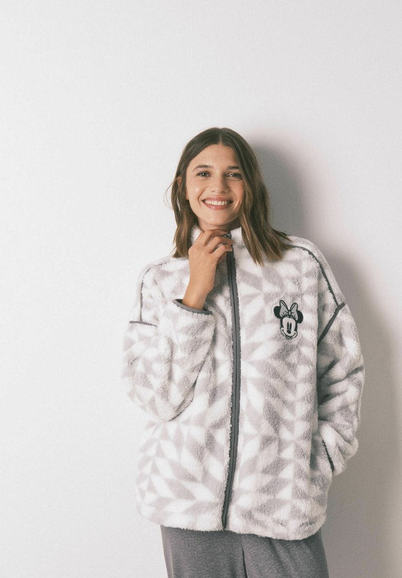 Faux fur jacket in gray with a diamond pattern. Features a zipper closure, stand-up collar, and a cartoon character embroidery on the chest.