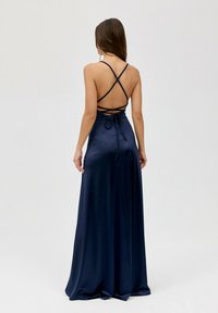 Námořnická modrá saténová večerní šaty s křížovým designem na zádech a detailem na zavazování, dlouhá splývavá sukně a minimalistické ramínka.