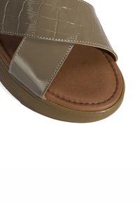 Beige synthetische slide sandaal met een glanzende krokodillenpatroon strap, bruine gevoerde voetbed en gestructureerde rubberen zool.