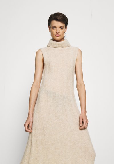 Vestido sem mangas em bege suave com um decote alto estilo cowl. Apresenta uma textura ribbed vertical e uma silhueta fluida e descontraída.