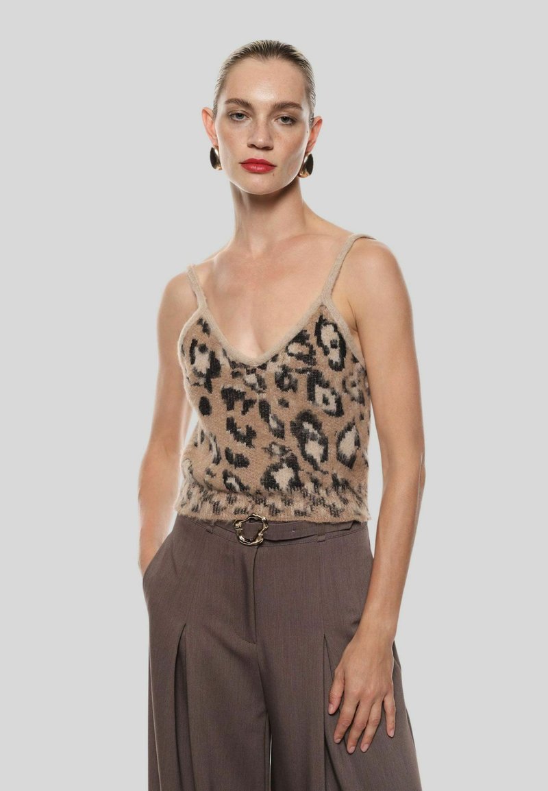 Top in maglia color sabbia con stampa leopardata nera, caratterizzato da un profondo scollo a V e spalline sottili, abbinato a pantaloni marroni a vita alta.