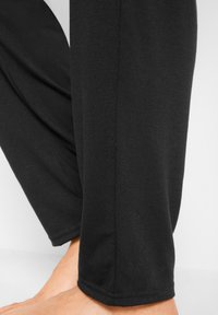 Pantaloni jogger in cotone nero composto, con una trama liscia, caratterizzati da un design a gamba affusolata e dettagli cuciti all'orlo.