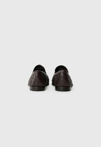 Brown woven slip-on shoes with a smooth leather heel. Open mesh design and flat black sole for comfort and breathability.