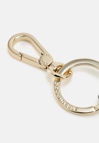 Portachiavi in oro con clip e anello circolare. L'anello presenta la scritta incisa "COCCINELLE". Finitura metallica liscia, senza motivi visibili.