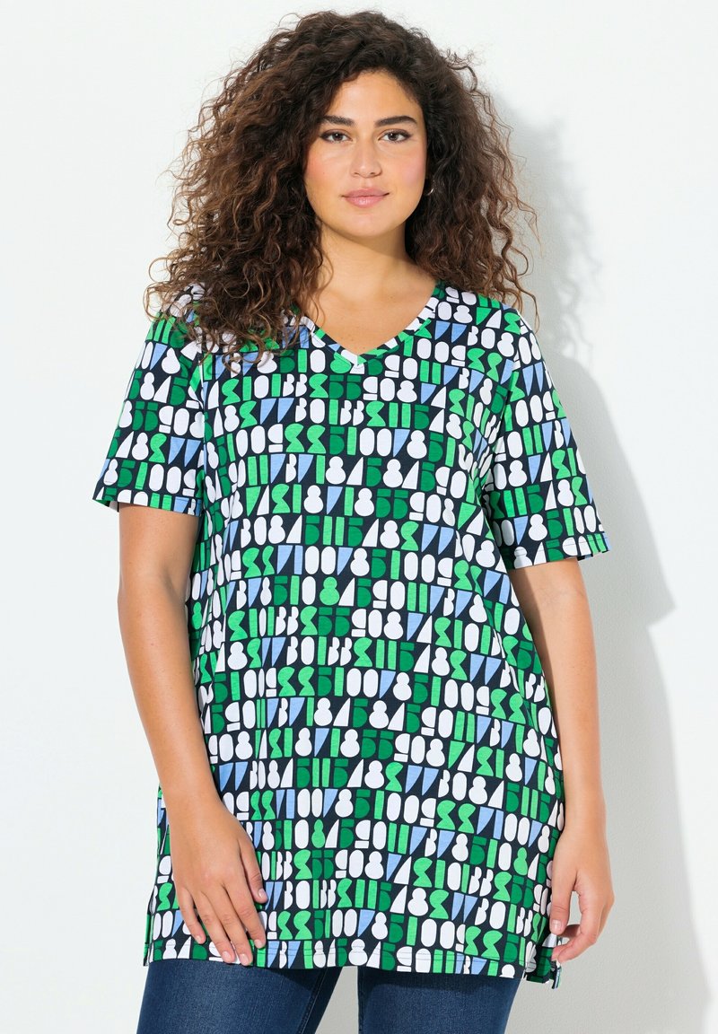 Korte mouw tuniek met een V-hals, voorzien van een geometrisch patroon in groen, blauw, wit en zwart op een lichte stof.