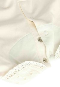 Cremfarbige Bluse mit einer durchgeknöpften Vorderseite, silbernen Druckknöpfen und einem detaillierten Spitzenbesatz am Saum, mit glatter Textur und weichem Stoff.