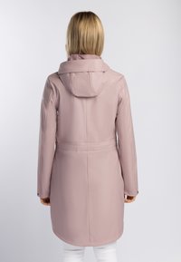 Trench-coat imperméable rose avec capuche, manches longues, taille cintrée et texture lisse. Comprend des boutons-pression aux poignets et une coupe mi-longue.
