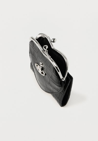 Czarna pikowana damska portmonetka z ekologicznej skóry, z srebrnym metalowym zapięciem i ozdobnymi elementami na froncie, o zaokrąglonym kształcie.