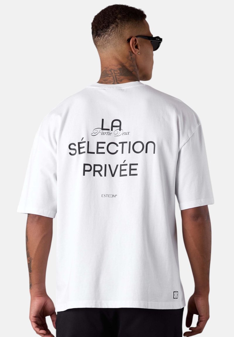 White cotton t-shirt featuring bold black text on the back: "LA Partie Deux SÉLECTION PRIVÉE" and a logo at the bottom corner. Short sleeves.