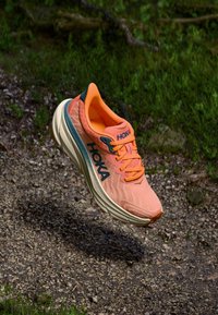 HOKA running shoe in bright orange and teal, featuring a textured upper, cushioned sole, and reinforced toe. Lightweight design, ideal for running.