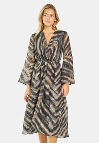 Langes, fließendes Kleid aus transparentem Stoff mit einem Chevron-Muster in Schwarz, Braun und Grau. Es hat einen tiefen V-Ausschnitt und Glockenärmel.