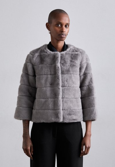 Jachetă din blană artificială gri, cu un design pătrățos, având un gât rotund și mâneci de trei sferturi, prezentată împreună cu pantaloni negri.