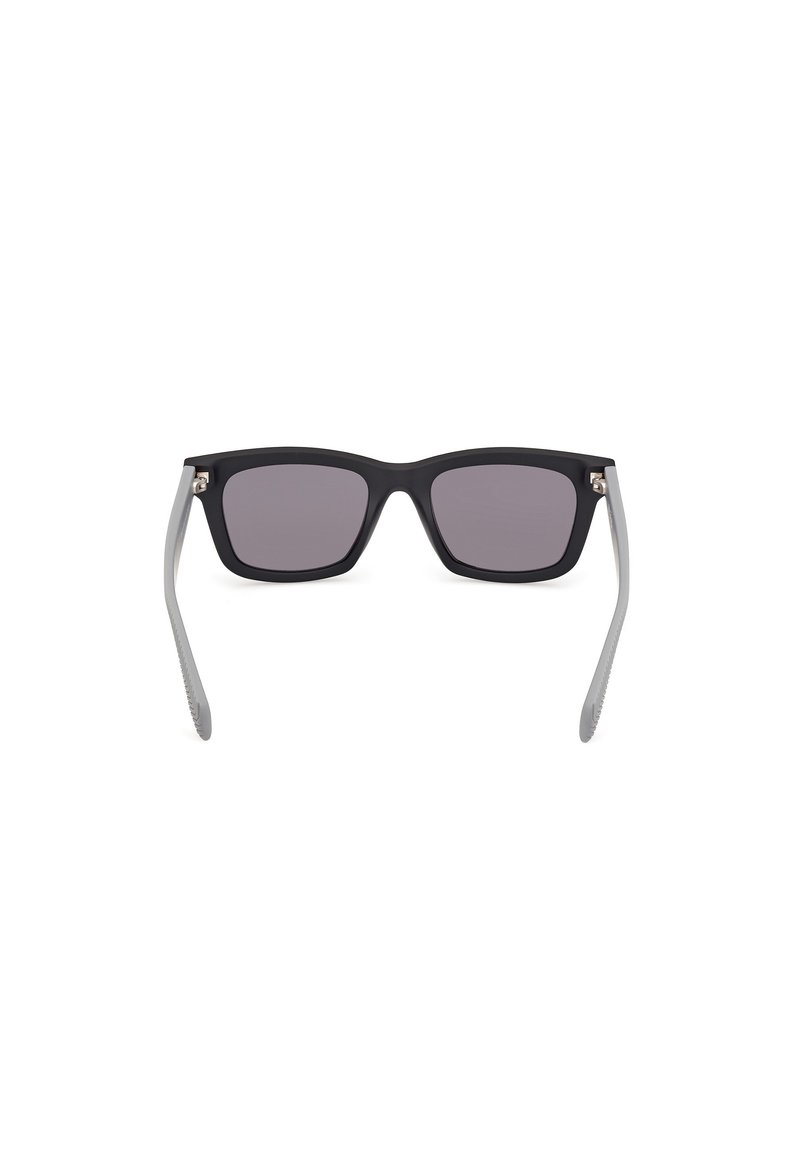 Zwarte vierkante zonnebril met grijze veren, voorzien van donker getinte lenzen en metalen accenten bij de scharnieren. Matte afwerking overal.